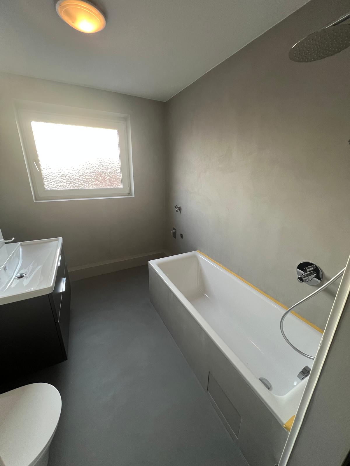 Badewanne und Wand in grauem Mikrozement
